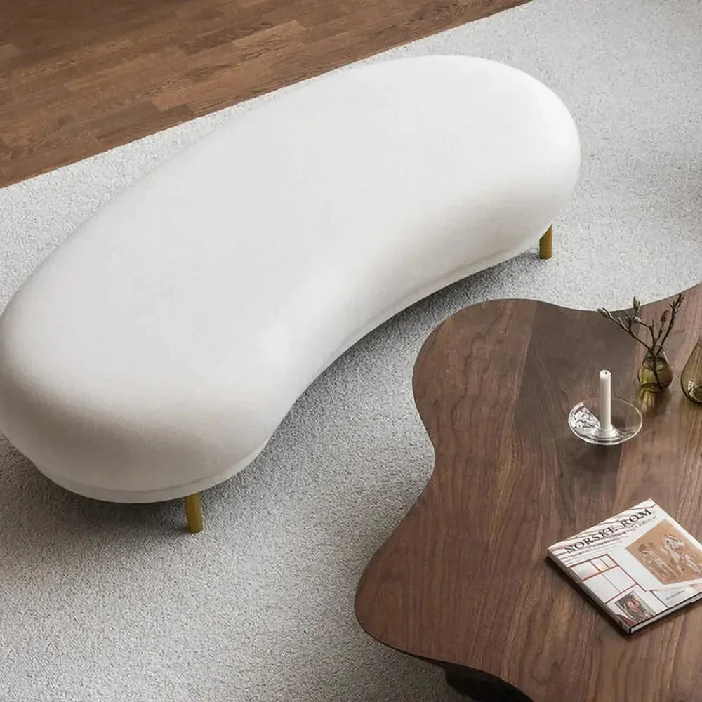 A curved velvet bench with golden legs