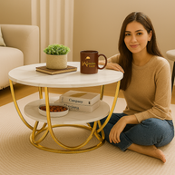 Woman sitting on the floor next to a small round table with decor items in a home setting.